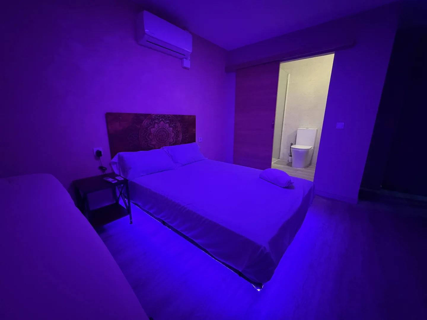 Sala con luz violeta y puerta abierta al baño