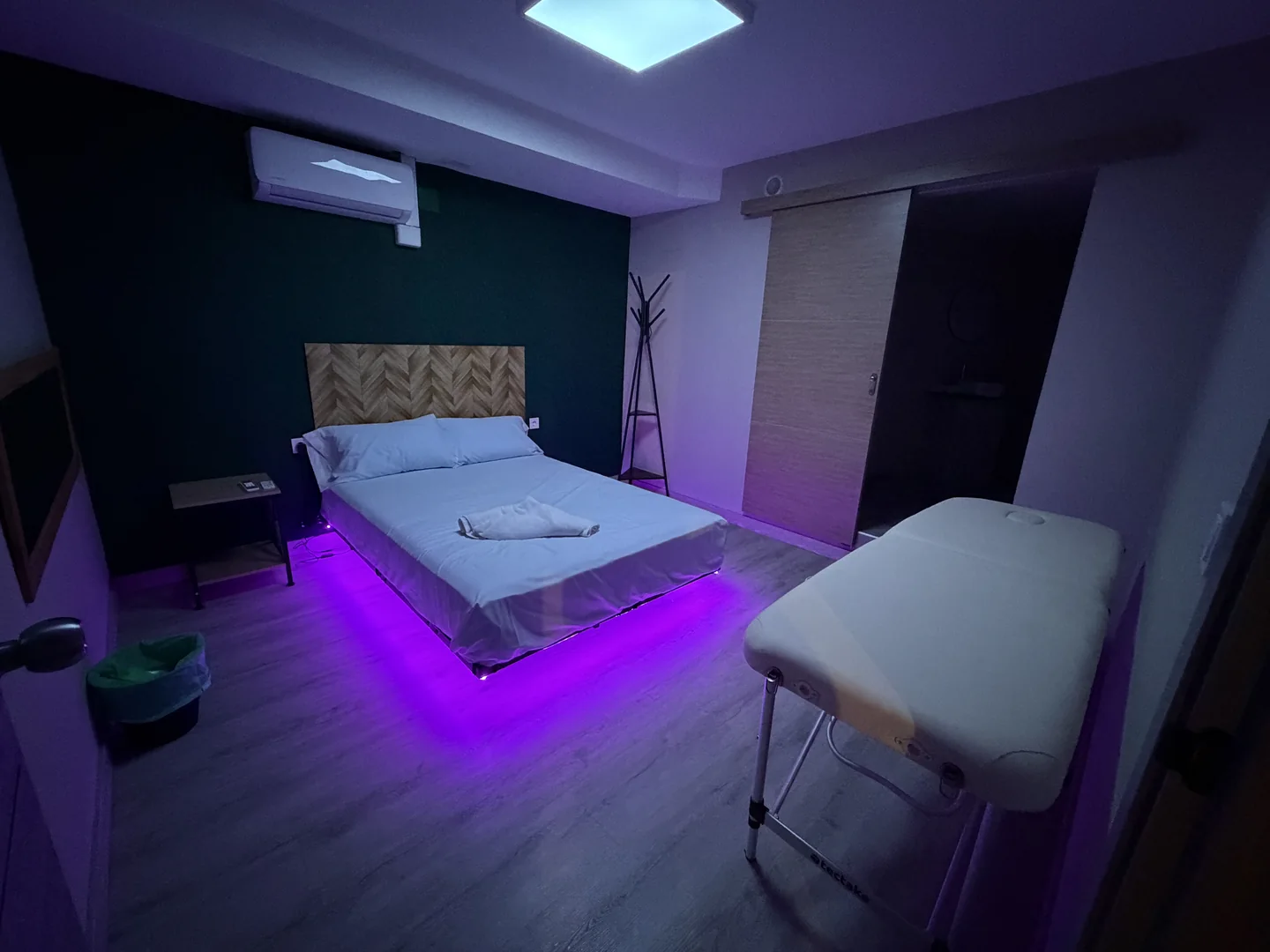 Vista amplia de una sala con iluminación violeta y camilla