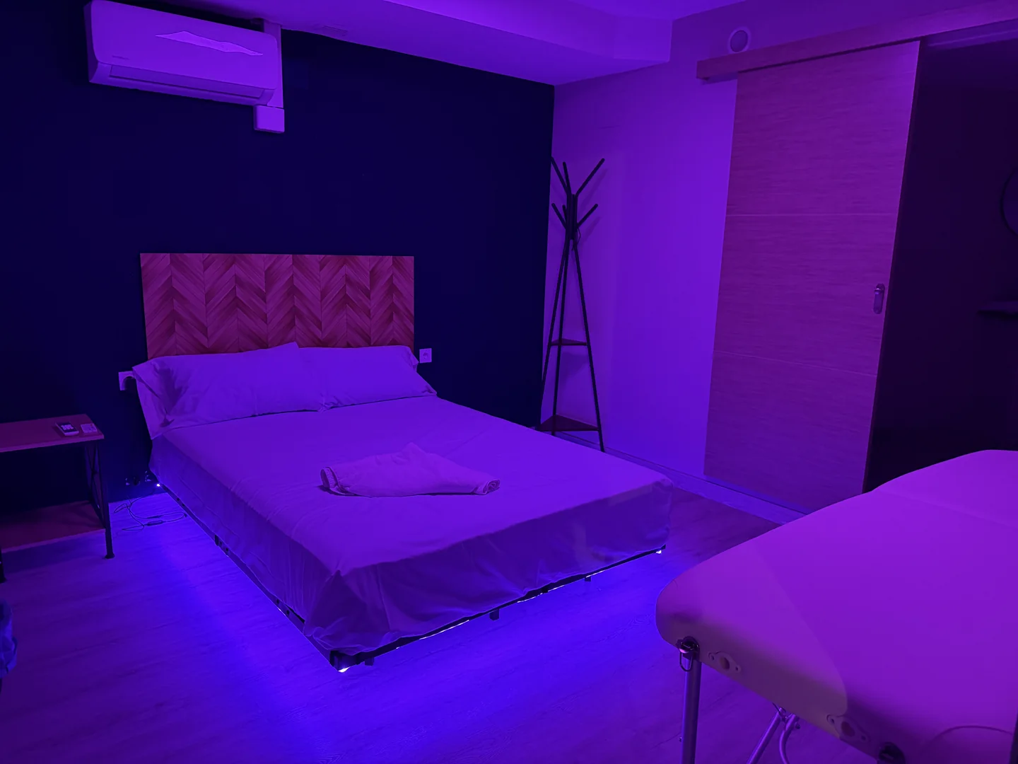 Sala de pared verde con luz violeta, textiles preparados y camilla